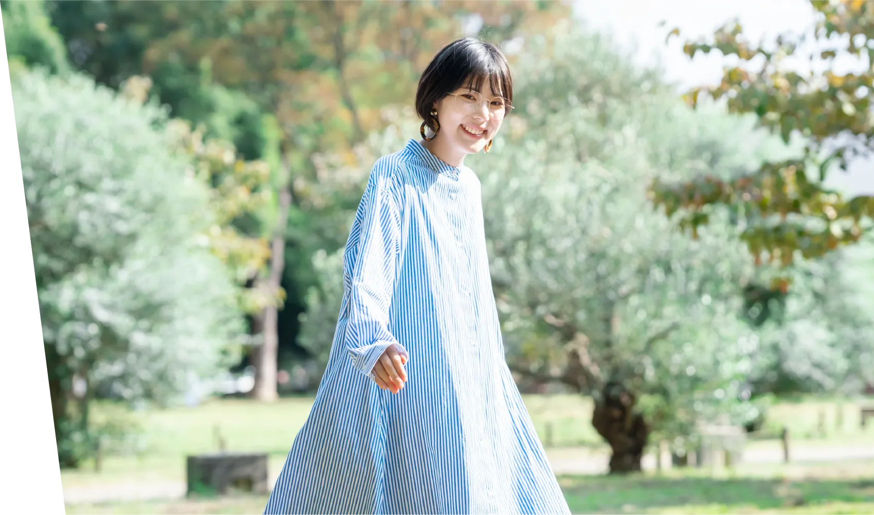 丸みのある黒縁のメガネをかけた女性が斜め右上を向き、ピースサインをする様子