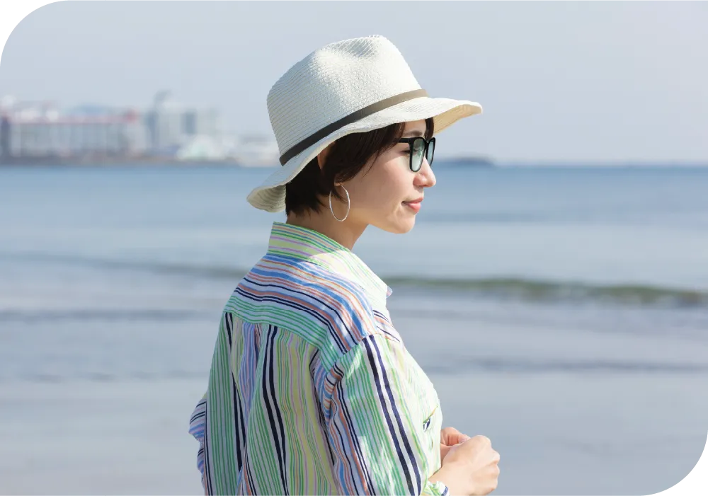 海辺で遠くを眺めるサングラスをかけた女性